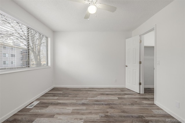 empty room with ceiling fan, hardwood / wood-style flooring, and a textured ceiling