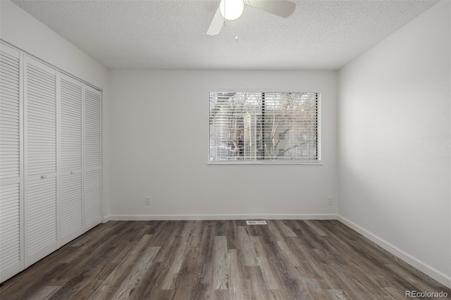 unfurnished bedroom with dark wood-type flooring, ceiling fan, a closet, and a textured ceiling