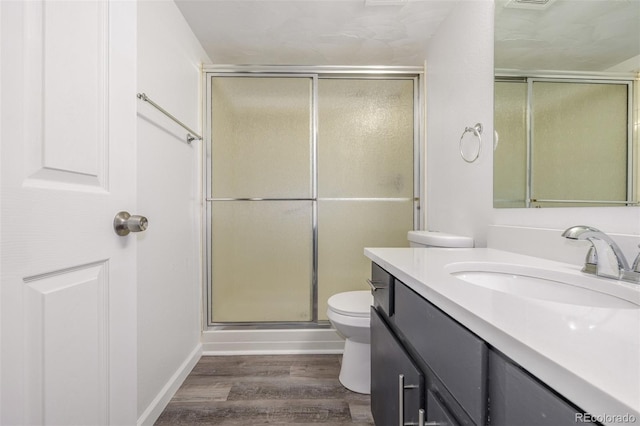 bathroom featuring vanity, hardwood / wood-style floors, a shower with shower door, and toilet