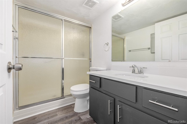 bathroom featuring vanity, wood-type flooring, toilet, and walk in shower