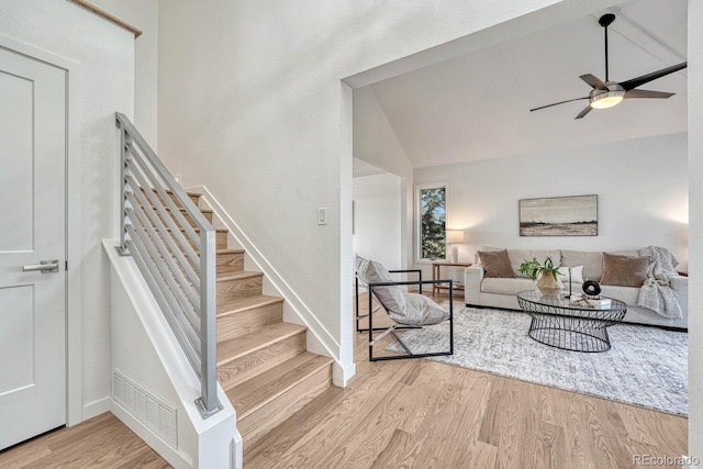 living room with light wood-type flooring, ceiling fan, and vaulted ceiling