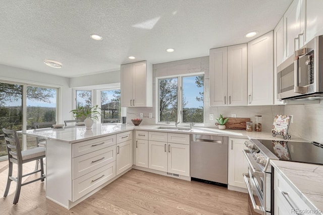 kitchen featuring white cabinets, kitchen peninsula, plenty of natural light, and stainless steel appliances