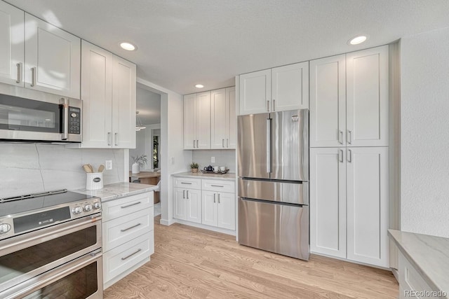 kitchen with white cabinetry, appliances with stainless steel finishes, tasteful backsplash, light wood-type flooring, and light stone counters