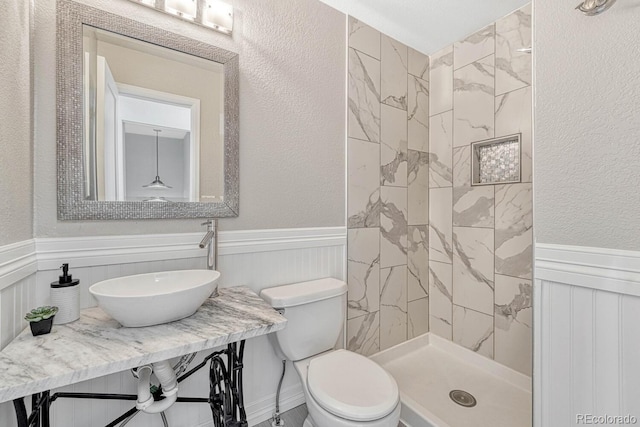 bathroom featuring sink, toilet, and a tile shower