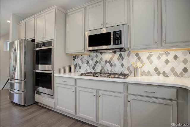 kitchen featuring white cabinets, appliances with stainless steel finishes, backsplash, and dark wood-type flooring