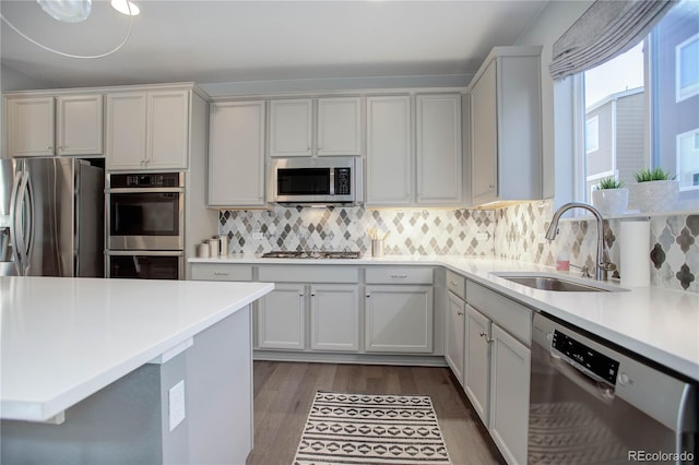 kitchen with white cabinets, sink, appliances with stainless steel finishes, tasteful backsplash, and wood-type flooring