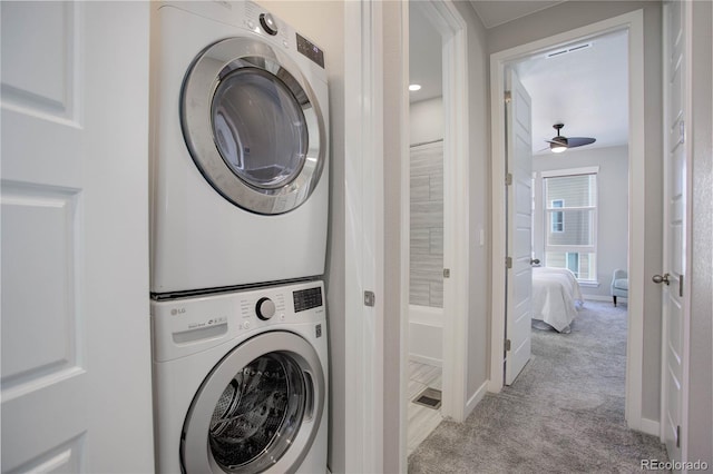 clothes washing area with ceiling fan, light colored carpet, and stacked washer and dryer