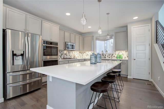 kitchen featuring decorative backsplash, a center island, hanging light fixtures, and appliances with stainless steel finishes