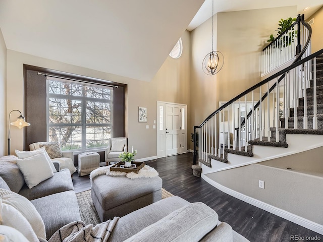 living room with dark wood-type flooring, high vaulted ceiling, and a notable chandelier