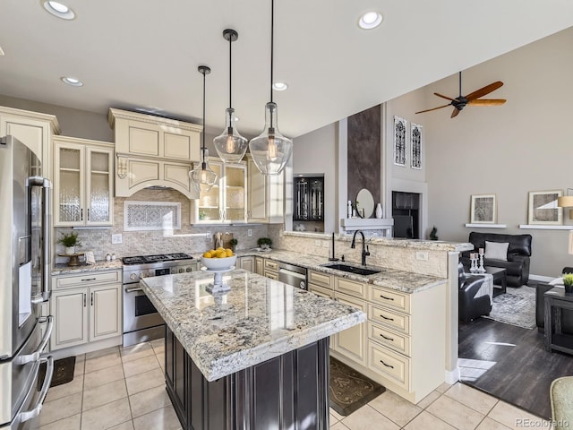 kitchen with appliances with stainless steel finishes, sink, hanging light fixtures, a center island, and cream cabinetry