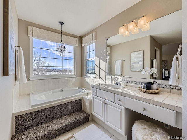 bathroom with an inviting chandelier, vanity, tile patterned flooring, and tiled tub