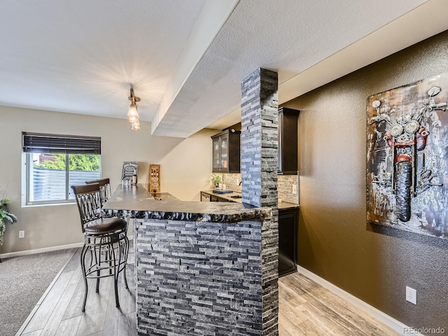 bar with dark brown cabinetry, light hardwood / wood-style flooring, and tasteful backsplash