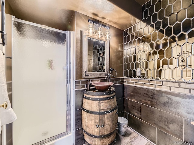 bathroom with sink, tile walls, and walk in shower