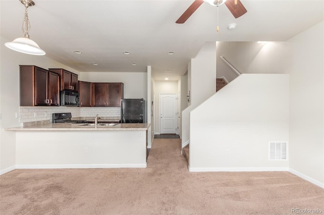 kitchen with sink, decorative light fixtures, black appliances, kitchen peninsula, and backsplash