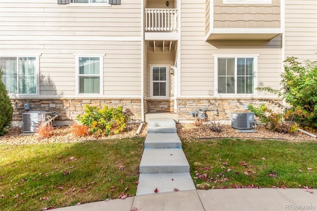 doorway to property with central AC and a yard