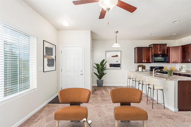 kitchen featuring a breakfast bar, sink, light carpet, pendant lighting, and decorative backsplash