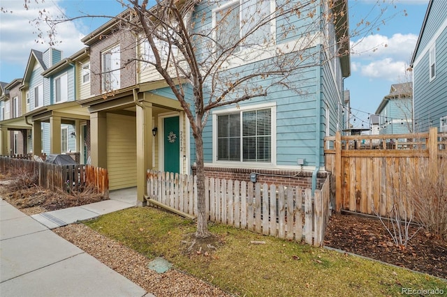 view of front of property featuring covered porch, fence, and brick siding