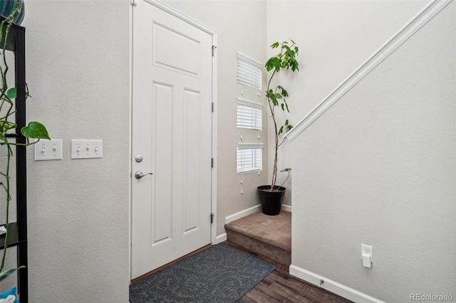 foyer entrance with dark wood-style floors and baseboards