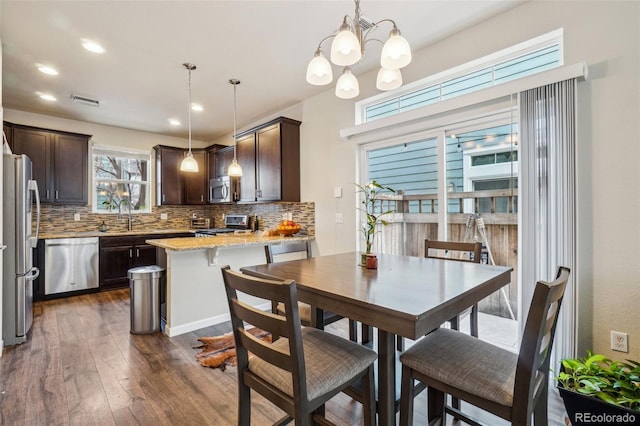 kitchen with appliances with stainless steel finishes, a sink, backsplash, and dark brown cabinets