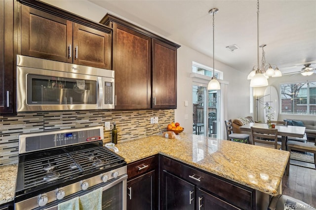 kitchen with open floor plan, appliances with stainless steel finishes, light stone counters, and a healthy amount of sunlight