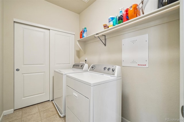 laundry room with laundry area, light tile patterned floors, baseboards, and washing machine and clothes dryer