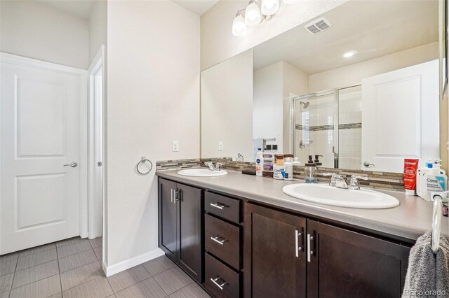 full bathroom featuring double vanity, a shower stall, visible vents, and a sink