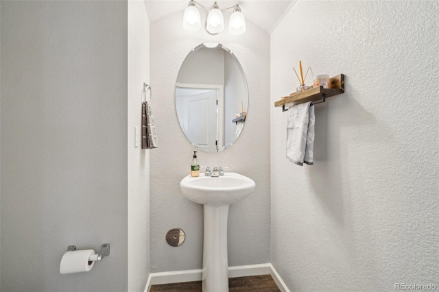 bathroom with a textured wall, a sink, and baseboards