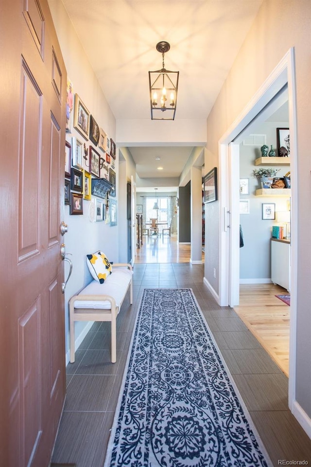 hall featuring wood-type flooring and a notable chandelier