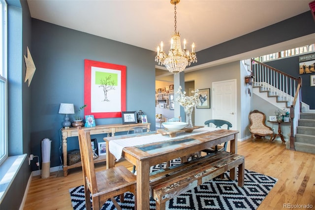 dining area with light wood-type flooring and a notable chandelier