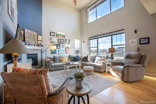 living room with a high ceiling, light wood-type flooring, and a healthy amount of sunlight