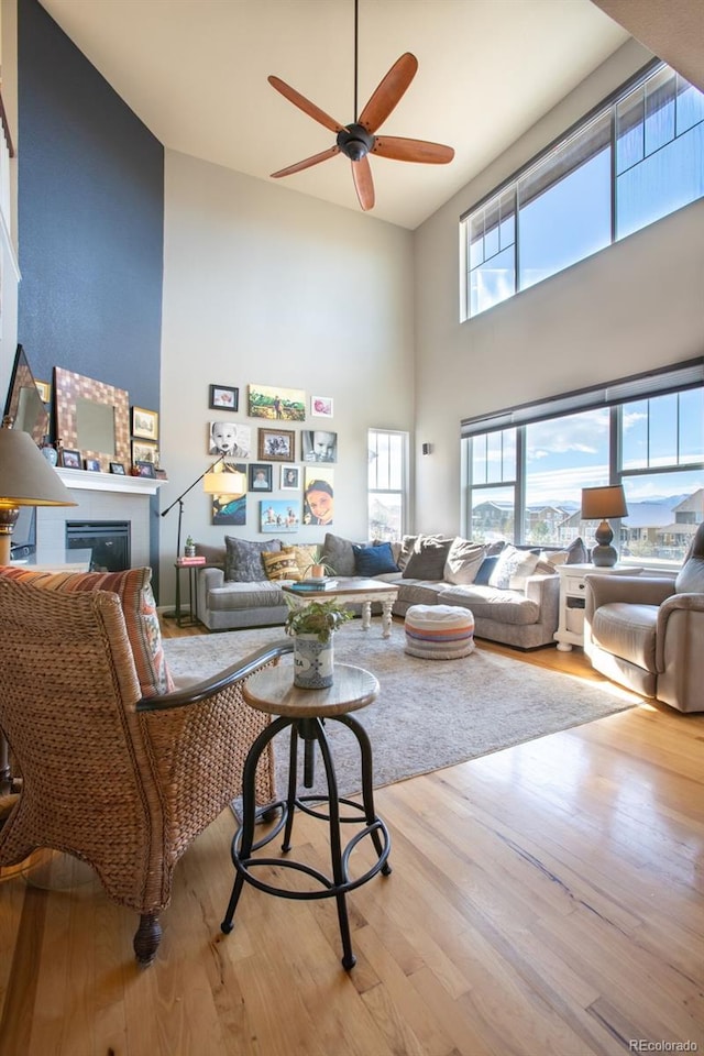 living room featuring a high ceiling, light hardwood / wood-style floors, and ceiling fan