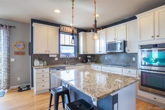 kitchen with pendant lighting, sink, light hardwood / wood-style flooring, a kitchen island, and stainless steel appliances