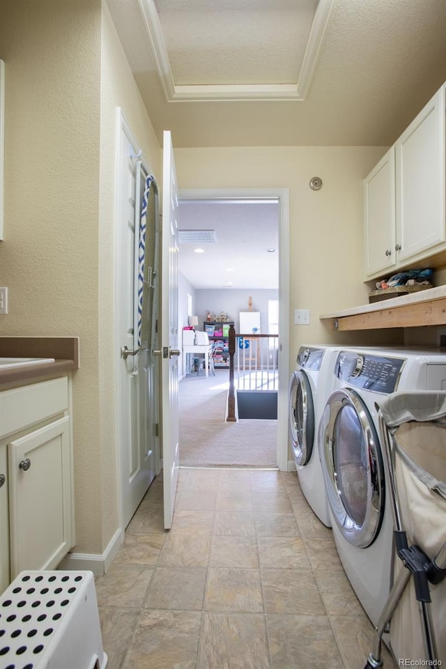 laundry room featuring cabinets, light colored carpet, a textured ceiling, and washing machine and dryer