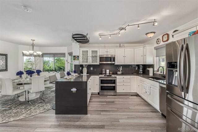 6260 Everett Ct Unit D, Arvada, CO 80004 - kitchen featuring appliances with stainless steel finishes, dark countertops, a sink, white cabinetry, and light wood-style floors