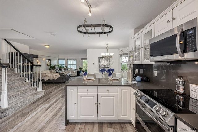 6260 Everett Ct Unit D, Arvada, CO 80004 - kitchen featuring stainless steel appliances, a peninsula, dark countertops, open floor plan, and white cabinets
