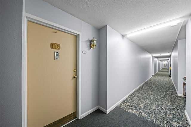 corridor with carpet, baseboards, and a textured ceiling