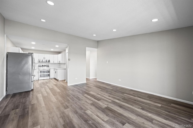 unfurnished living room with baseboards, wood finished floors, and recessed lighting