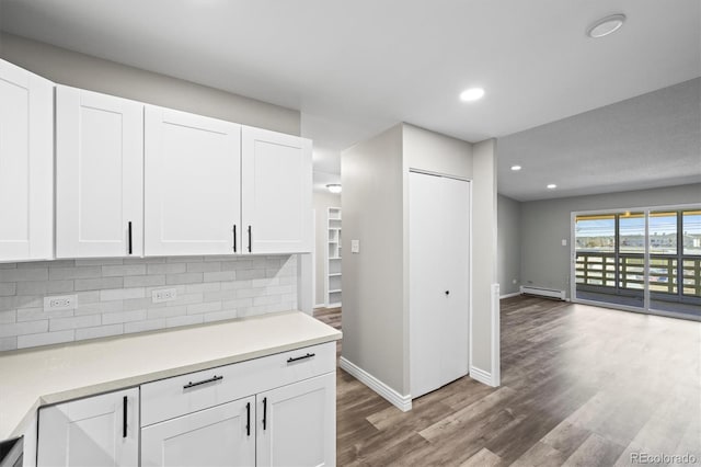 kitchen with dark wood-style floors, a baseboard radiator, light countertops, backsplash, and white cabinetry