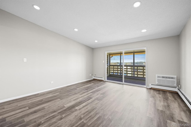 unfurnished room featuring recessed lighting, a wall mounted AC, a baseboard heating unit, wood finished floors, and baseboards