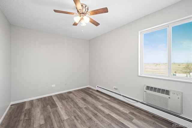 empty room with a baseboard heating unit, wood finished floors, a ceiling fan, and baseboards