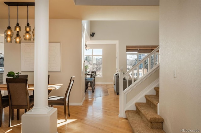 dining space with light hardwood / wood-style floors and decorative columns