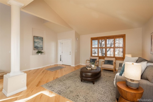 living room featuring decorative columns, wood-type flooring, and lofted ceiling