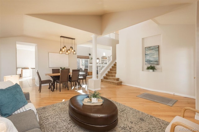 living room with ornate columns, vaulted ceiling, and wood-type flooring