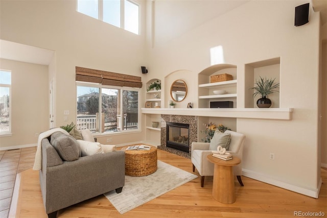 living room with built in shelves, a healthy amount of sunlight, a fireplace, and light hardwood / wood-style flooring