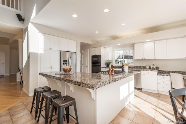 kitchen featuring a center island, white cabinets, dark stone counters, and black appliances