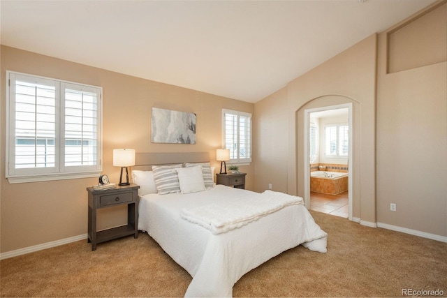 carpeted bedroom featuring vaulted ceiling and ensuite bathroom