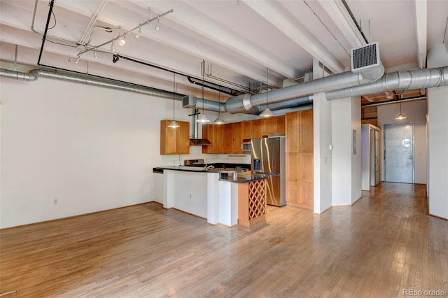 kitchen with a peninsula, dark countertops, visible vents, light wood-style floors, and stainless steel appliances