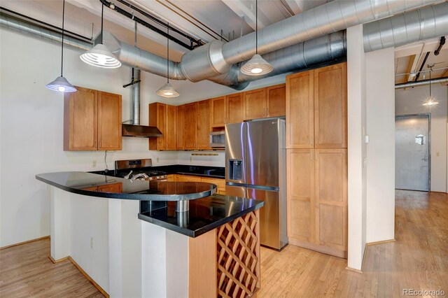 kitchen with hanging light fixtures, light wood-type flooring, dark countertops, and stainless steel appliances