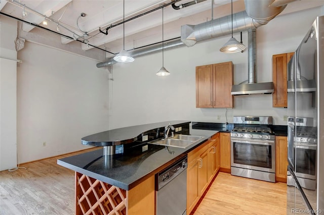 kitchen with a sink, appliances with stainless steel finishes, wall chimney exhaust hood, and dark countertops
