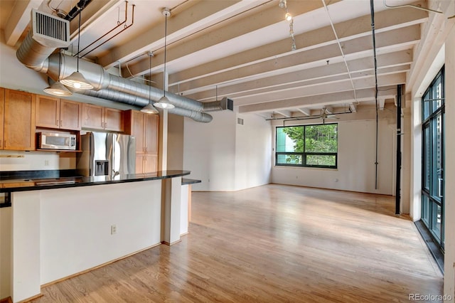 kitchen with open floor plan, light wood finished floors, dark countertops, and stainless steel appliances